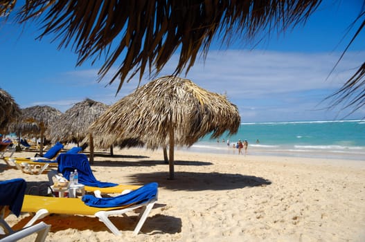 Many parasols made out of palm leafs on beach.