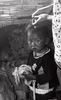 A Nepali boy under her mother's hands, looking