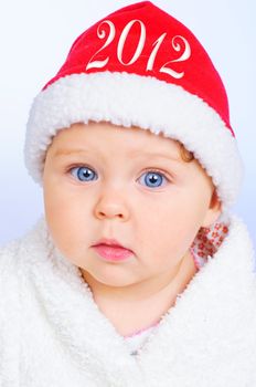 Surprised baby girl in santa claus hat with future year 2012