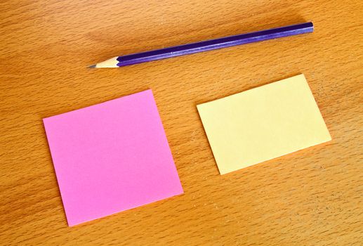 Yellow and pink memo with pencil on wood table