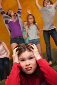 Annoyed little girl among others who shout and jump on furniture