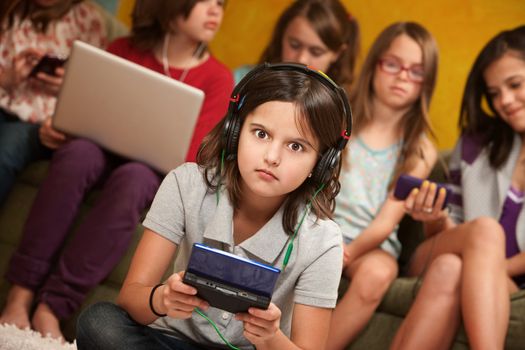 Surprised little girl with headset and portable gaming console with friends