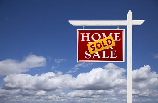 Red Sold Home For Sale Real Estate Sign Over Beautiful Clouds and Blue Sky.