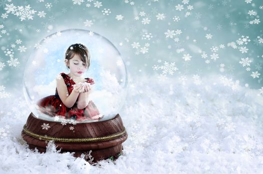 Little girl inside a snow globe blowing snow out of her hands. Copy space available.