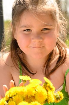 A young girl is holding a bouquet of dandelions.