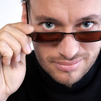Studio portrait of a young adult man looking over his sunglasses