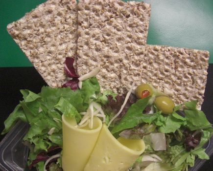 slices of crispbread with cheese, mixed salad and olives