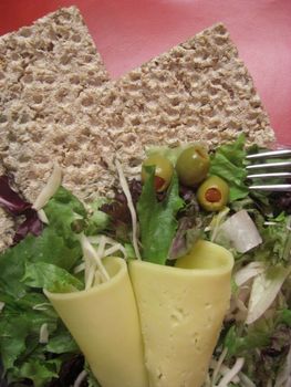 slices of crispbread with cheese, mixed salad and olives, upright format