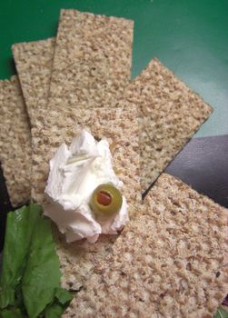 slices of crispbread with cream cheese and an olive - upright format