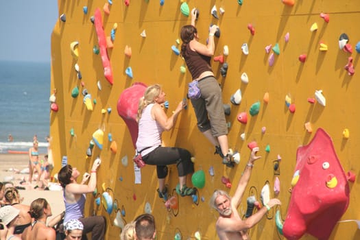 Annual Bouldering Competition on Scheveningen beach. Participants climbing artificial rock face.