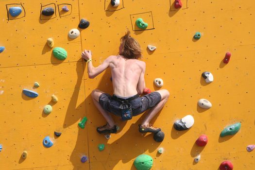 Annual Bouldering Competition on Scheveningen beach. Participant climbing artificial rock face.