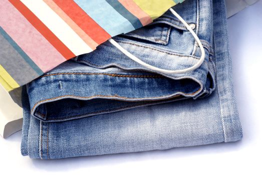 Jeans in striped paper bag on white background.
