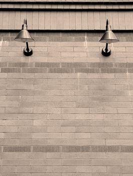 Black sconce lights on brick wall in sepia tone.