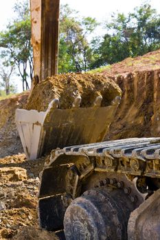 Back hoe standing in mining with raised bucket full of sand