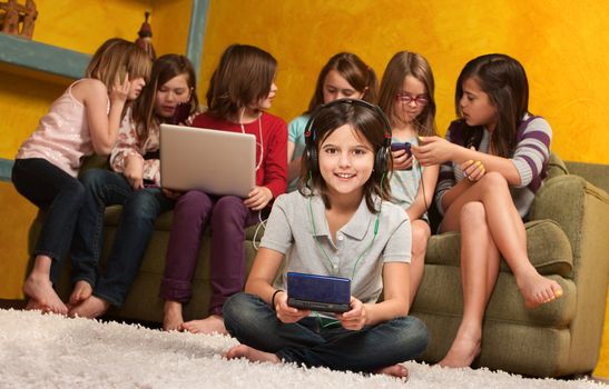 Smiling little girl playing video game on portable console with her friends 