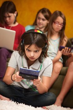 Little Caucasian girl focused on her portable gaming console
