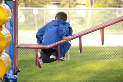 A young boy playing at the playground climbing on a metal structure