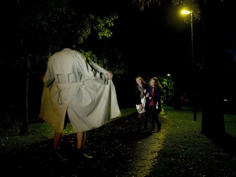 Two women laughing at a Flasher at night in the park