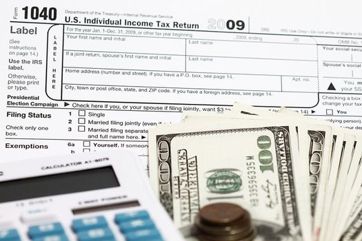 1040 tax form with calculator and dollars.