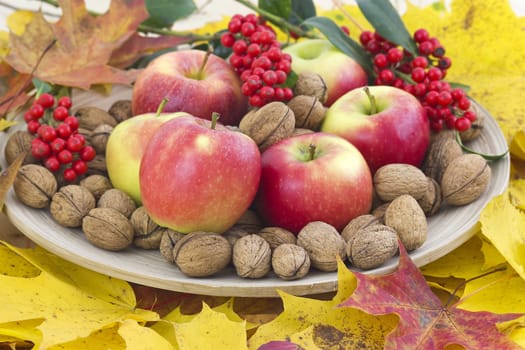 beautiful arrangement of autumn leaves and red apples and walnuts