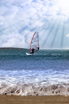 person windsurfing in the maharees in county kerry ireland during a storm in rays of sunshine