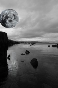 black and white night scenic view in kerry ireland of rocks and sea with mountains against a beautiful blue cloudy sky