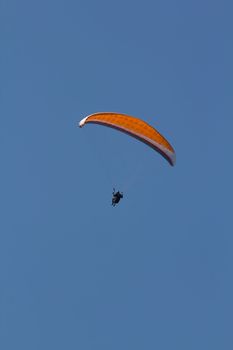 A Paraglider flying from a mountain on a warm summer afternoon