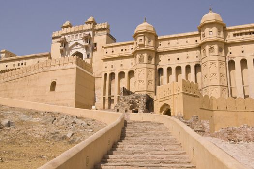 Steps leading up to the imposing front entrance (Suraj Pol) to Amber Fort. Large honey coloured Moghul style building. Jaipur, Rajasthan, India.