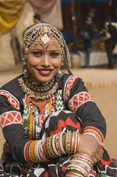Beautiful Kalbelia dancer in ornate black costume trimmed with beads and sequins at the annual Sarujkund Fair near Delhi in India.