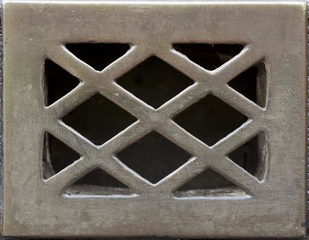 Weathered and scratched metal grate for door peep hole.