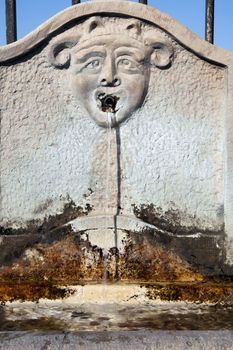 Stone fountain with face sculpture and flowing water.