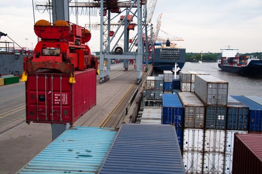 a container ship is (un)loaded by a large cargo crane in a harbor
