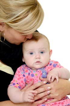 Mother is looking down on her sweet baby while kissing her. Taken on a white background.