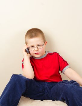 the small boy in glasses uses mobile phone