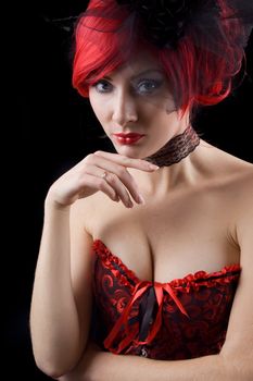 Red-headed gothic woman in black and red corset isolated on black