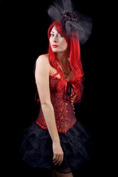 Red-headed gothic woman in black and red corset isolated on black