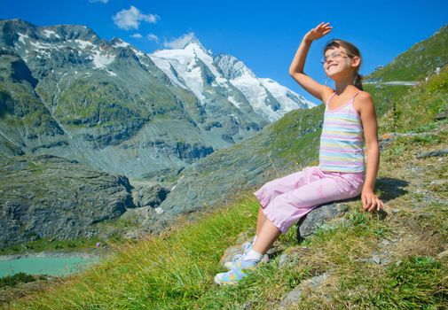 girl hiker sitting on a rock and looking at the mountains