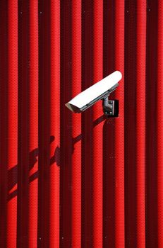 Video surveillance camera on a red wall