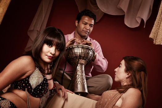 Two beautiful belly dancers with handsome Indian tabla player