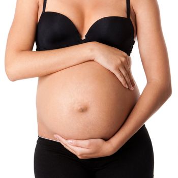 Beautiful pregnant belly of motherhood with hands around wearing black bra and underwear, isolated.