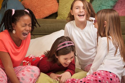 Group of four girls at a sleepover laugh out loud 