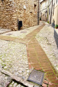 Sidewalk between old homes paved with the cobblestones