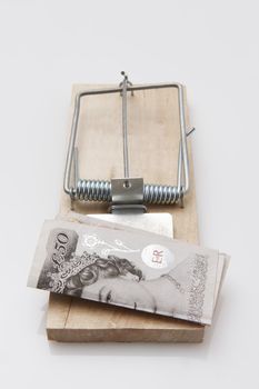 fifty pound note set on a mousetrap on white background