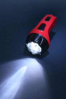 Red plastic luminous flashlight on dark background