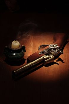 Extinguished candle near ancient pistol on wooden surface