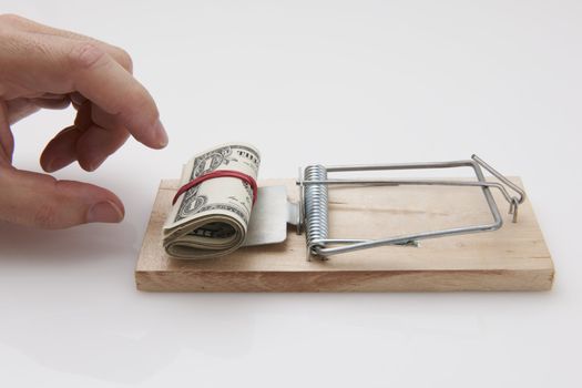 Male hand taking rolled up dollar bills from mousetrap