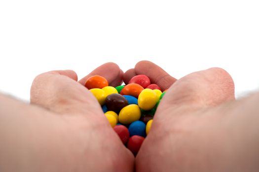 Colorful bonbons in hand on white background