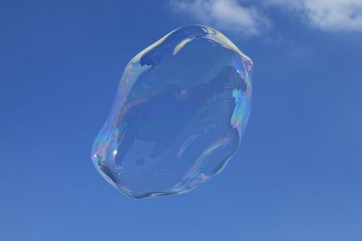 Image of a big bubble against a blue sky with few clouds.