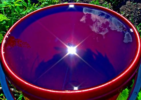 reflection sun in pail with water