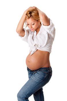 Beautiful new happy mother in late pregnancy wearing fashion jeans and white shirt, looking at tummy, isolated.